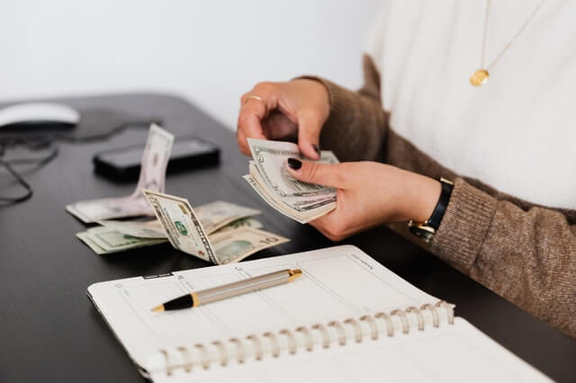 Payroll clerk counting money at a table